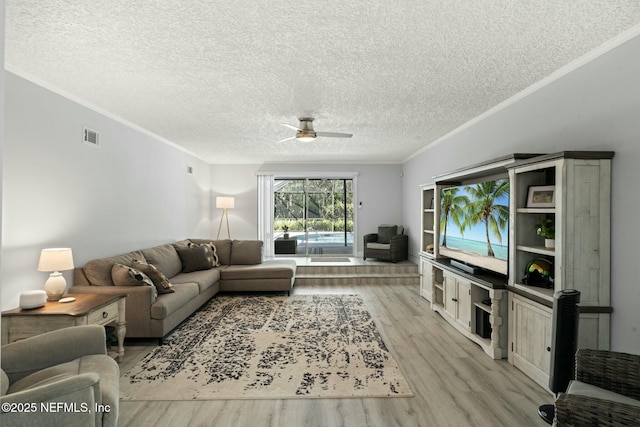 living area featuring visible vents, light wood finished floors, ceiling fan, a textured ceiling, and crown molding