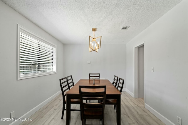 dining room featuring a notable chandelier, visible vents, baseboards, and light wood-style floors