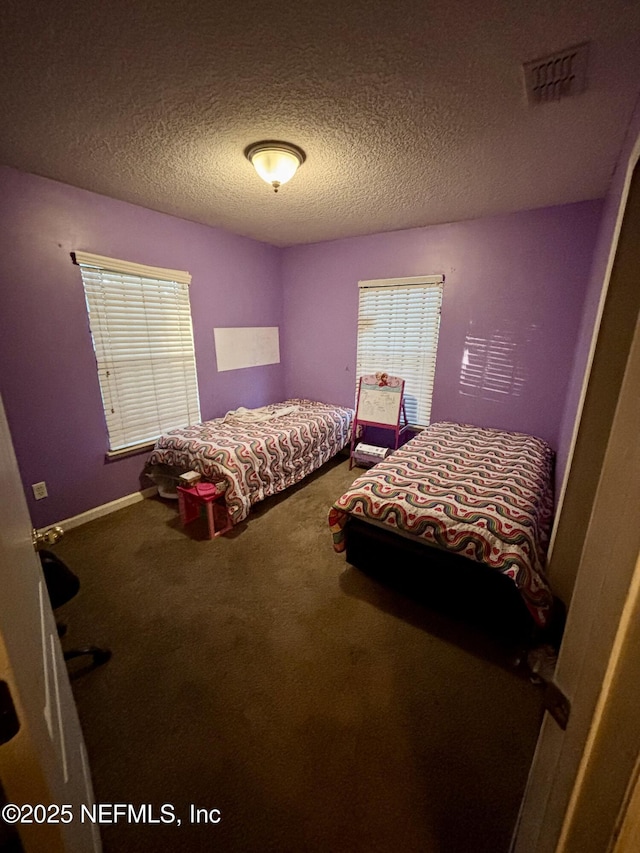 bedroom featuring visible vents, baseboards, carpet, and a textured ceiling