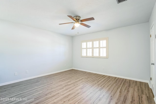 empty room with visible vents, a ceiling fan, baseboards, and wood finished floors