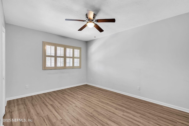 empty room with a textured ceiling, a ceiling fan, baseboards, and wood finished floors