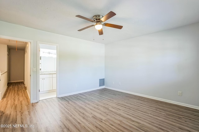 empty room featuring light wood finished floors, visible vents, ceiling fan, baseboards, and attic access