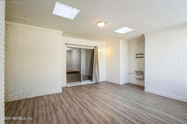 unfurnished bedroom with a closet, ornamental molding, brick wall, and wood finished floors