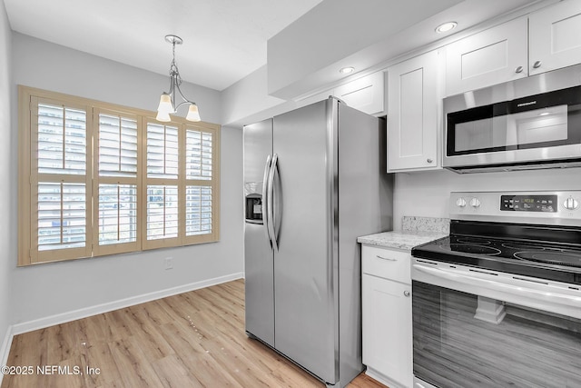 kitchen with pendant lighting, stainless steel appliances, light wood-style floors, white cabinets, and baseboards