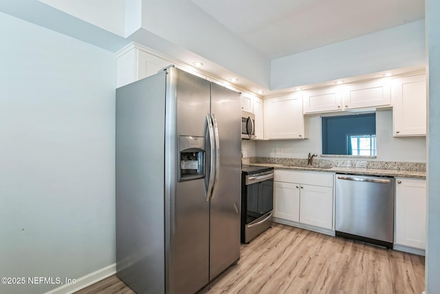 kitchen with a sink, stainless steel appliances, light wood-style flooring, and white cabinets