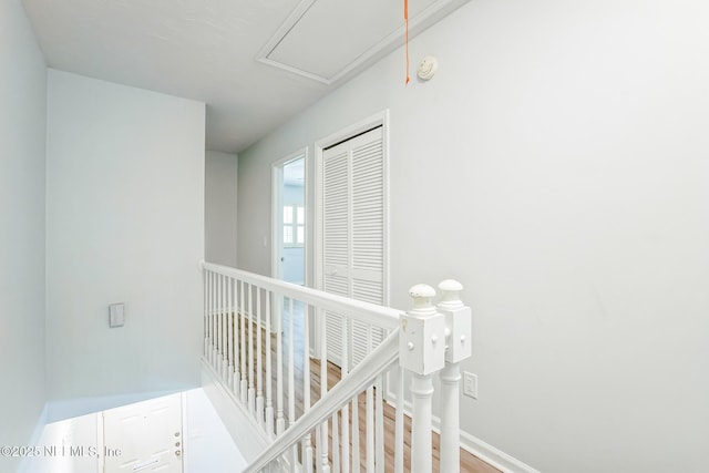 corridor featuring an upstairs landing, baseboards, and wood finished floors