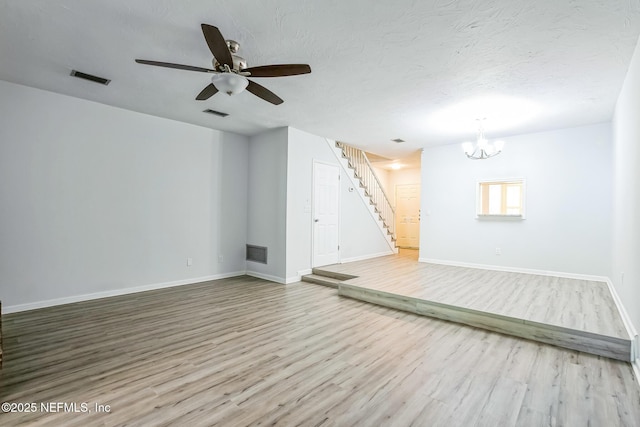 unfurnished room featuring visible vents, a textured ceiling, wood finished floors, and stairs