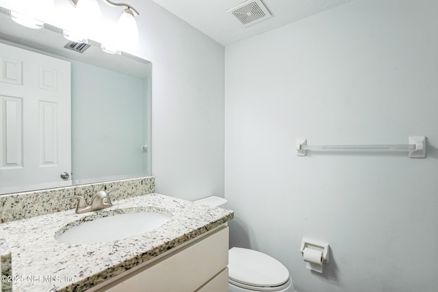 bathroom with visible vents, toilet, and vanity