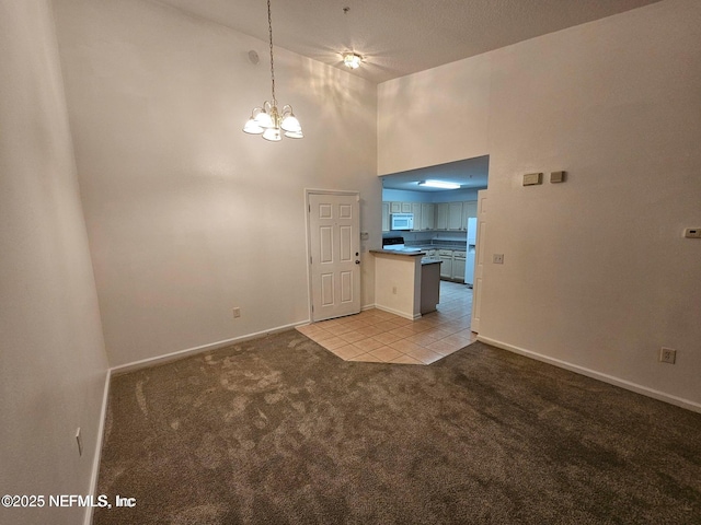 interior space featuring a high ceiling, an inviting chandelier, light tile patterned flooring, baseboards, and light colored carpet