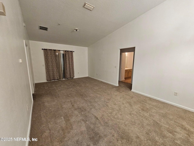 empty room with vaulted ceiling, baseboards, visible vents, and carpet floors