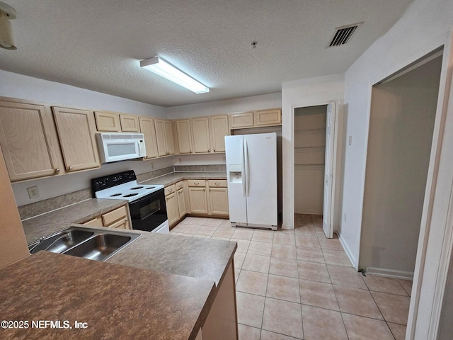 kitchen featuring visible vents, light brown cabinetry, light tile patterned floors, white appliances, and a sink