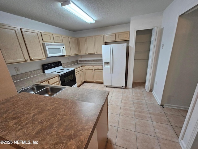 kitchen featuring light brown cabinetry, a sink, a textured ceiling, white appliances, and light tile patterned floors