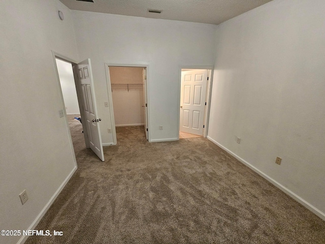 unfurnished bedroom featuring visible vents, a closet, carpet, baseboards, and a spacious closet