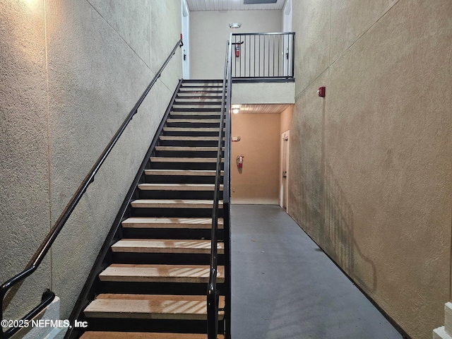 stairway featuring a high ceiling and concrete floors