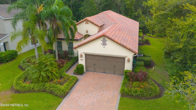 mediterranean / spanish-style house featuring decorative driveway, a garage, stucco siding, and a tiled roof