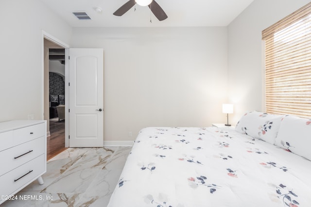 bedroom with a ceiling fan, visible vents, marble finish floor, and baseboards