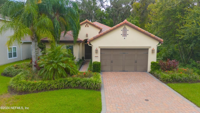 mediterranean / spanish home with stucco siding, a front lawn, decorative driveway, a garage, and a tiled roof