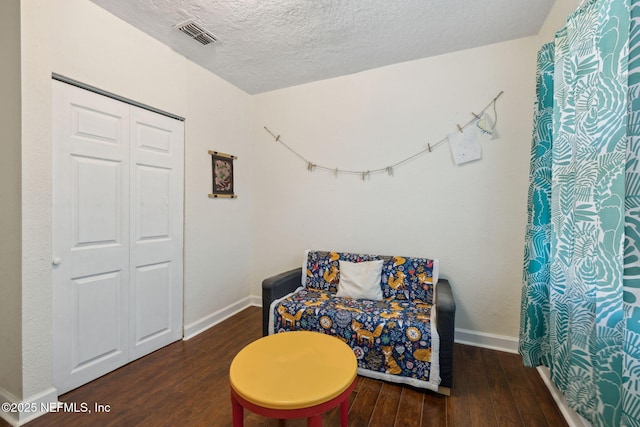 sitting room featuring visible vents, a textured ceiling, baseboards, and wood finished floors