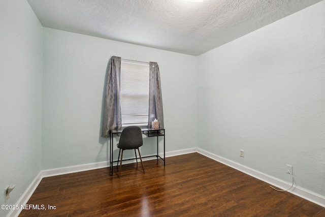 spare room with wood finished floors, baseboards, and a textured ceiling