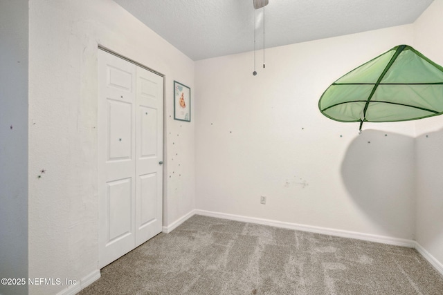 carpeted spare room featuring a ceiling fan, baseboards, and a textured ceiling