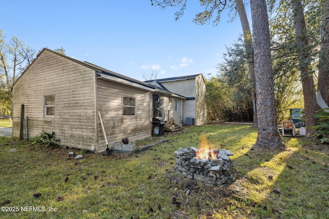 view of home's exterior featuring a lawn, entry steps, and an outdoor fire pit