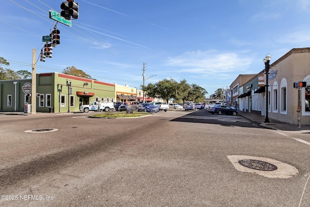 view of road featuring sidewalks, curbs, street lights, and traffic lights