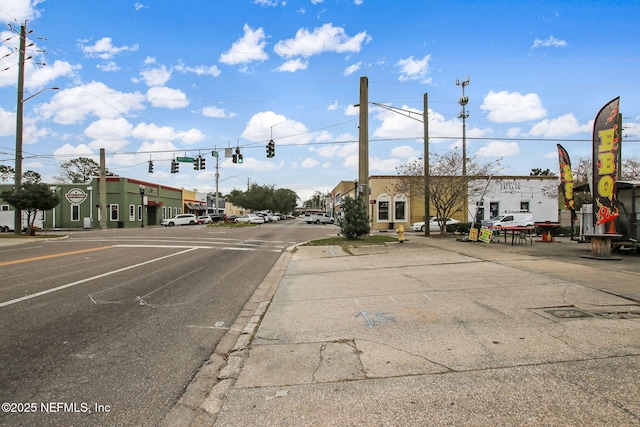 view of road featuring street lights, curbs, sidewalks, and traffic lights