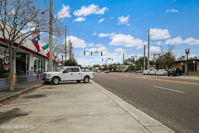 view of street with curbs, traffic lights, street lighting, and sidewalks