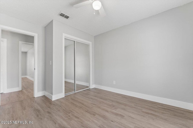 unfurnished bedroom with visible vents, baseboards, wood finished floors, a closet, and a textured ceiling