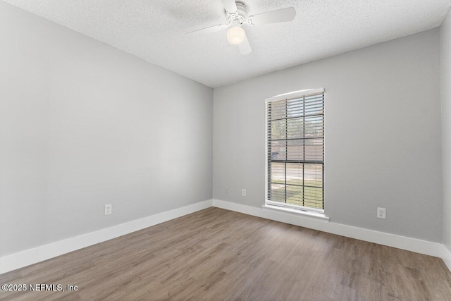 empty room featuring ceiling fan, wood finished floors, baseboards, and a textured ceiling