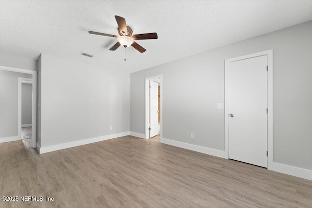 spare room featuring visible vents, a textured ceiling, baseboards, and wood finished floors