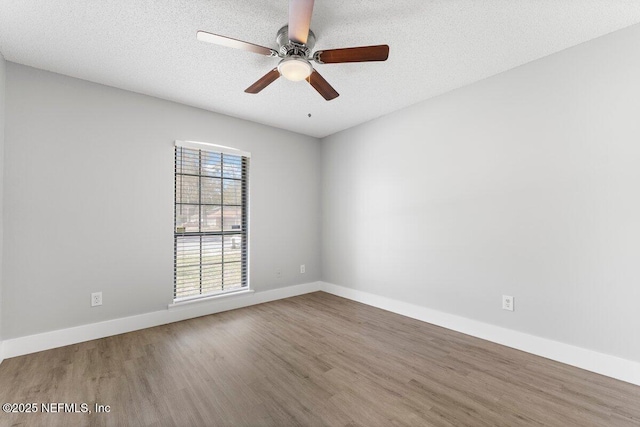 spare room with baseboards, a textured ceiling, wood finished floors, and a ceiling fan