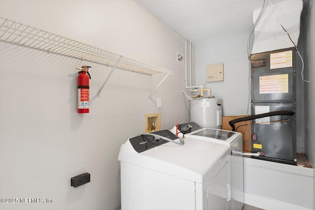 laundry room with washer and dryer, heating unit, electric water heater, a textured ceiling, and laundry area