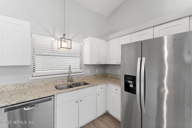 kitchen featuring light stone counters, appliances with stainless steel finishes, white cabinetry, and a sink