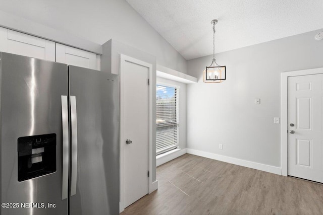 kitchen with white cabinetry, vaulted ceiling, wood finished floors, and stainless steel fridge with ice dispenser