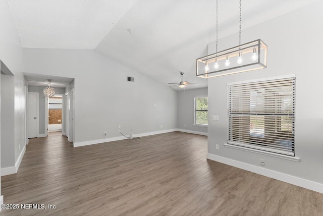 unfurnished living room featuring wood finished floors, ceiling fan with notable chandelier, visible vents, and lofted ceiling