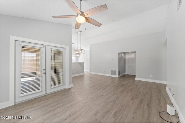 unfurnished living room with visible vents, french doors, lofted ceiling, and wood finished floors