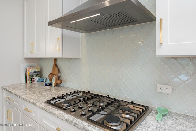 kitchen with stainless steel gas cooktop, decorative backsplash, white cabinets, and wall chimney exhaust hood