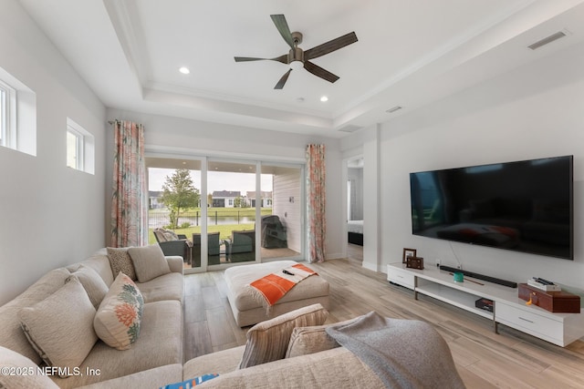 living room featuring a tray ceiling, plenty of natural light, and wood finished floors