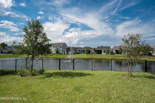 view of yard with a residential view, fence, and a water view