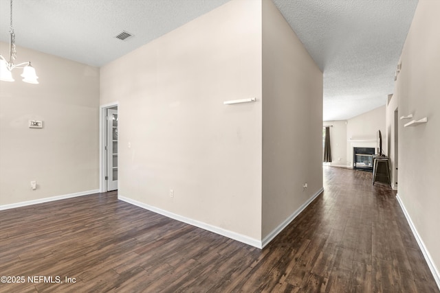corridor with visible vents, a notable chandelier, a textured ceiling, dark wood finished floors, and baseboards