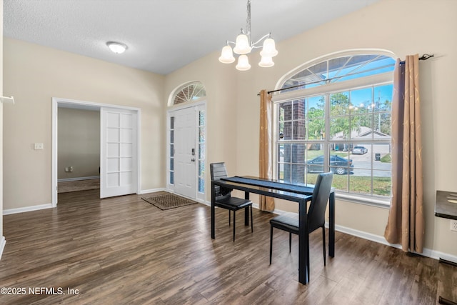 dining room featuring dark wood-style floors, baseboards, a textured ceiling, and a chandelier