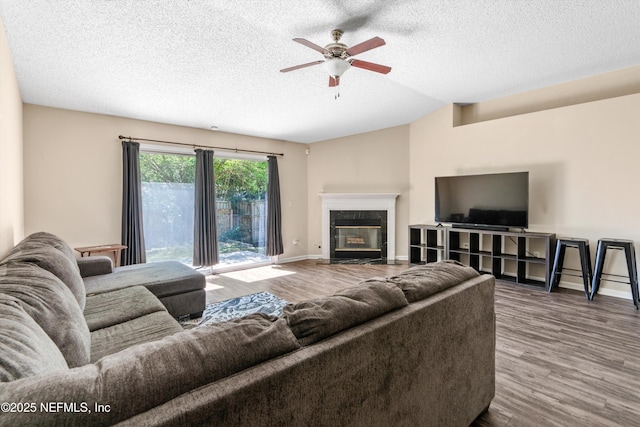 living area with wood finished floors, baseboards, a high end fireplace, ceiling fan, and a textured ceiling