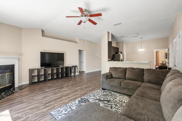 living room with visible vents, a textured ceiling, wood finished floors, a high end fireplace, and ceiling fan