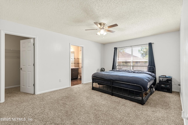 bedroom featuring a spacious closet, ceiling fan, baseboards, carpet floors, and ensuite bathroom