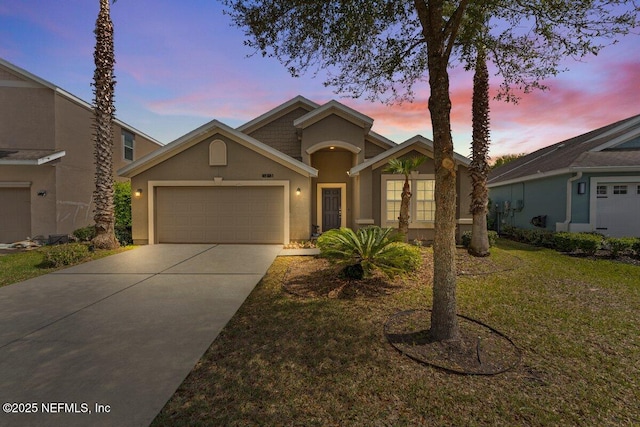 view of front of house featuring stucco siding, a front lawn, a garage, and driveway