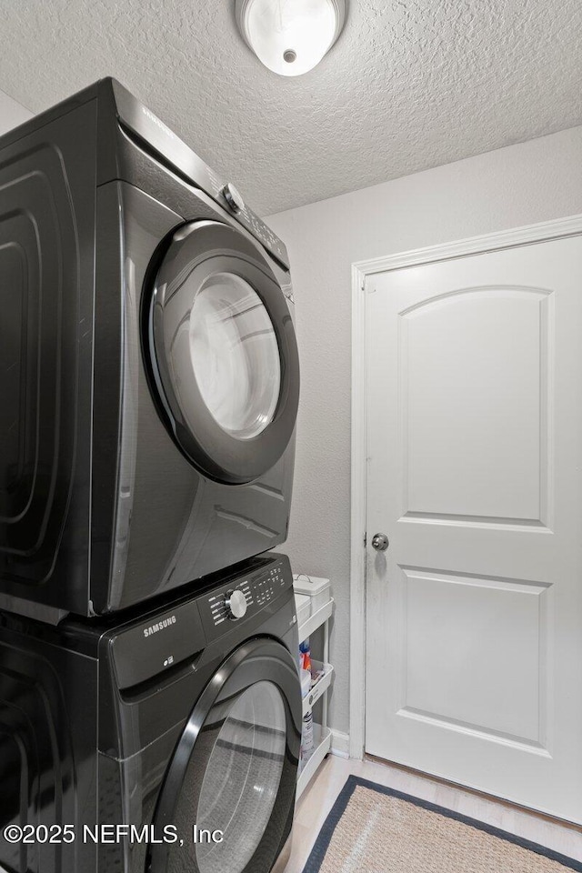 clothes washing area featuring stacked washer / dryer, a textured ceiling, and laundry area