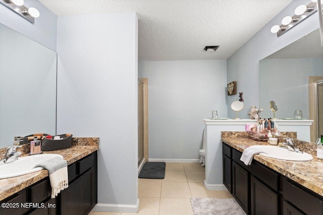 full bath with tile patterned floors, a stall shower, a textured ceiling, and a sink