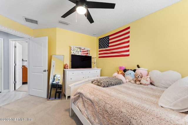 carpeted bedroom with visible vents, a textured ceiling, and a ceiling fan