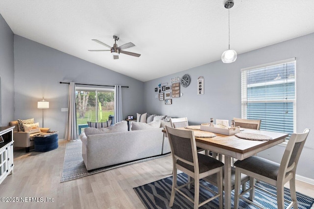 dining space featuring light wood finished floors, baseboards, a ceiling fan, and lofted ceiling